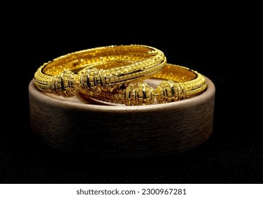 A pair of gold bangles jewelry isolated on dark background