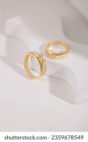 Pair of gold wedding rings with diamonds and matte surface on white textured background. Original design wedding ring bands - Shutterstock ID 2359678549