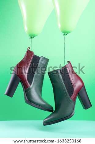 a pair of green and red autumn leather women's shoes hanging on green balloons on a green background.