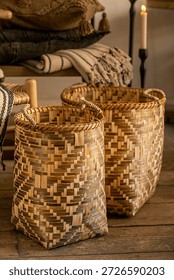 A pair of handcrafted wicker baskets featuring an intricate brown and natural geometric weave, styled in a warm rustic interior with wooden flooring and soft ambient lighting.