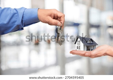 A pair of hands exchanges keys, symbolizing the joy of acquiring a new home in a modern real estate setting.