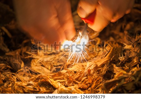 A pair of hands making a fire with flint and steel