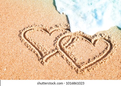 A pair of hearts painted on the sand in summer at the sea