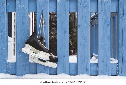 Pair Of Hockey Skates Hanging On Doorstep Railing