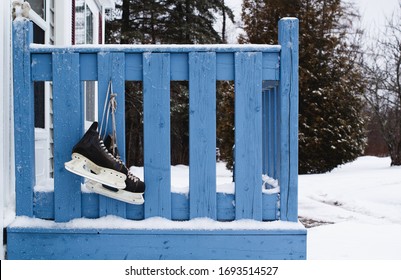 Pair Of Hockey Skates Hanging On Doorstep Railing