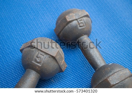 Pair of iron dumbbell 5 kilograms on blue yoga mat (Fitness exercise equipment)