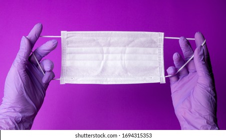 Pair Of Latex Medical Gloves On Purple Background. Protection Concept. COVID-19. Facial Masks On The Pile. Epidemic Background. Shortage Of Facial Masks At Drug Store. Quarantine Background. 