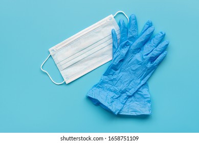 Пара латексных медицинских перчаток и хирургическая маска для ушей на синем фоне. Концепция защиты