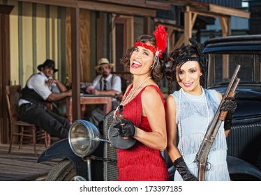 Pair of laughing 1920s gangster women with guns