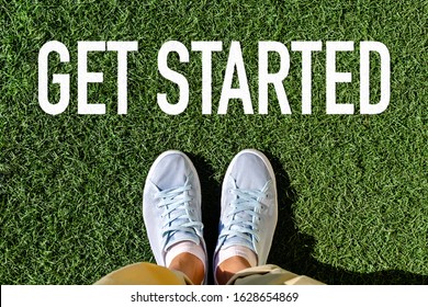 Pair Of Legs On Green Grass Before The Inscription - Get Started. View From Above. The Concept Of Motivation For The Beginning Of Changes In Life, The Way Out Of The Comfort Zone.