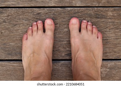 Pair Of Light Skinned, Slightly Tanned Feet Seen From Above With All Ten Toes On A Wooden Floor