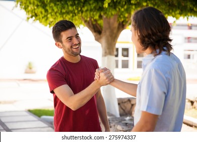 Pair Of Male Friends Greeting Each Other With A Handshake At School