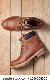 Pair Of Men Leather Brown Waterproof Boots For Winter Or Autumn Hiking On Wooden Background. Mens Fashion, Trendy Footwear.