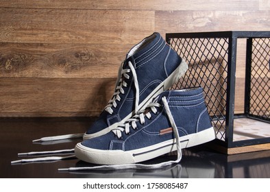 Pair Of Men's Tennis Shoes On Black Table And Wooden Background With Grid