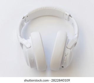 A pair of modern white overear wireless headphones rests on a plain white background