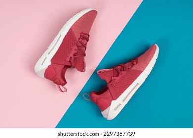 Pair of new pink sneakers, sport shoes on blue and pink background. Pink womens sport, running shoes
