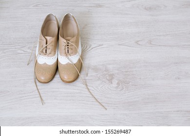 Pair of new unlaced womans shoes on a white wooden floor 