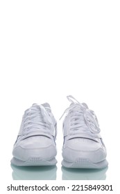 Pair Of Of New White Sneakers Placed Against White Background. Vertical Shot