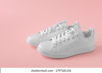 Pair Of New White Stylish Sneakers On Pink Pastel Background. New White Leather Sneakers Sports Shoes. Sports Shoes For Running, Tennis, Jogging. Copyspace. Side View