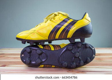 A pair of old football boots old yellow football shoes placed on a wooden board, gray background Soft light