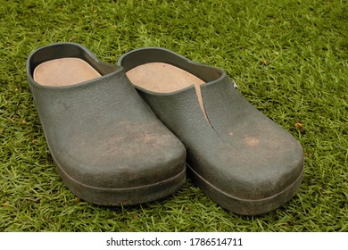 Pair Of Old Split And Damaged Gardening Clogs, Isolated On Grass