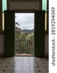 A pair of open green doors frames a distant mountain view across a tiled courtyard in Barcelona, Spain.