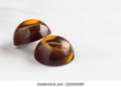 Pair of painted handcrafted chocolate bonbons. Delicious dessert on a white background with copyspace