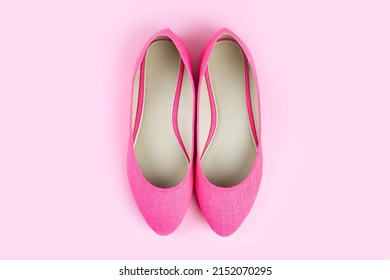 Pair of pink ballet shoes isolated on pastel pink background. Women's shoes, stylish classic textile pink court shoes. Top view, flat lay, mockup with copy space for text. Fashion concept.