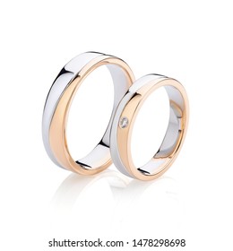 Pair of pink gold and silver wedding rings isolated on white background. Female ring decorated with diamond. Silver and gold wedding ring bands