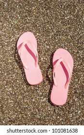 A pair of pink sandals in the sand
