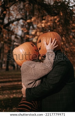 The pair of pumpkin heads kiss in the park. Jack o lantern halloween costume for a couple. Romantic Halloween. 