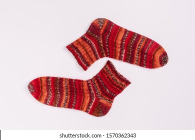 Pair Of Red And Orange Striped Knitted Socks From Sectional Yarn. Warm Winter Wool Socks. Flat Lay, Copy Space. Knitting And Crocheting Concept. Self-made Clothes. Merino Wool. 