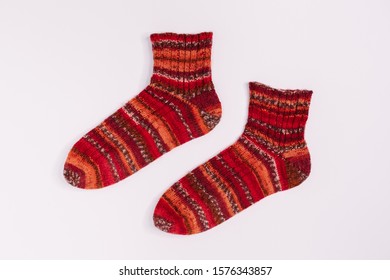 Pair Of Red And Orange Striped Knitted Socks From Sectional Yarn. Warm Winter Wool Socks. Flat Lay, Copy Space. Knitting And Crocheting Concept. Self-made Clothes. Merino Wool. 