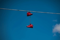 A Pair Of Red Tennis Shoes Hang From A Telephone Wire.