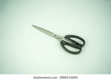 Pair of scissors lying on a clean white surface