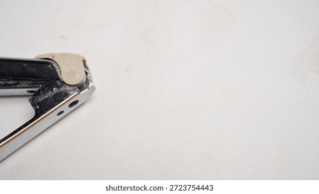 A pair of scissors with a white handle and a white tip is open. The scissors are lying on a white surface