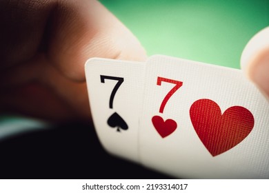 A pair of sevens in a man's hand close up. Seven of hearts and seven of spades, poker background. - Shutterstock ID 2193314017