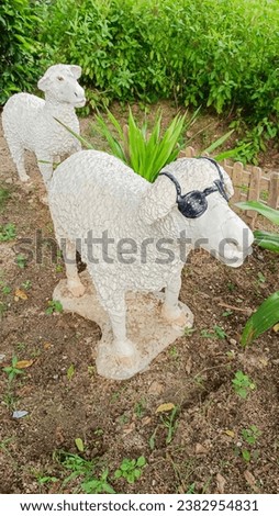 A pair of sheep and a lamb in the grass. Ceramic White plaster statuette. The plot of the lamb lovers. sheep wearing glasses