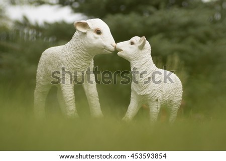 A pair of sheep and a lamb in the grass. Ceramic White plaster statuette. The plot of the lamb lovers.