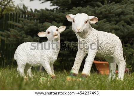A pair of sheep and a lamb in the grass. Ceramic White plaster statuette. The plot of the lamb lovers.