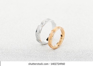 Pair of silver mens ring and pink gold womens ring with diamonds  on white glitter background. Wedding rings with matte surface. Copy space