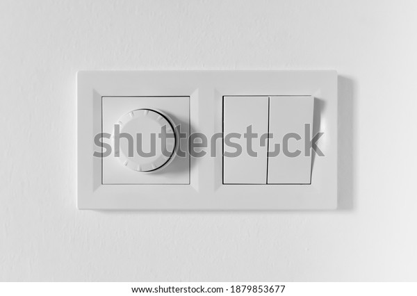 Pair of simple light switches with dimmer.\
Inexpensive plastic mechanical double switch with thermostat\
against white wall. Old air conditioner control panel. Smart Home\
Climate Control Appliances