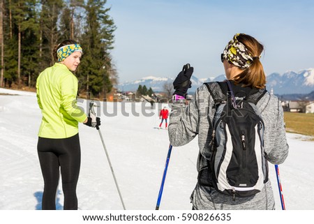 Pair of skiiers taking a break and talking.