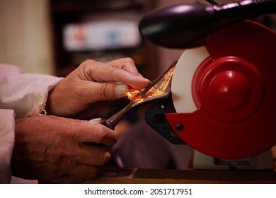 A pair of skilled mans hands sharpening a woodworking chisel on a bench grinding wheel. - Powered by Shutterstock