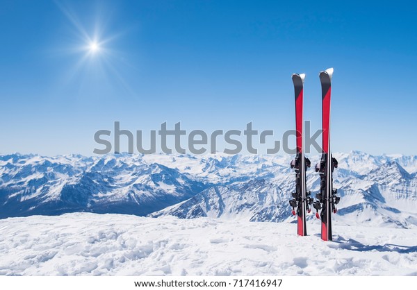 Pair of skis in snow with copy space. Red skis
standing in snow with winter mountains in background. Winter
holiday vacation and skiing concept.
