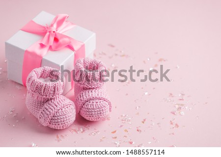Pair of small baby socks and gift box on pink background with copy space for your warm message, baby shower, first newborn party background, copy space