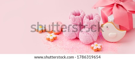 Pair of small pink baby socks, cookies, gift box on pink background with copy space for your warm message, baby shower, first newborn party background, copy space, monochrome, banner