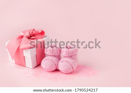 Pair of small pink baby socks and gift box on pink background with copy space for your warm message, baby shower, first newborn party background, copy space, monochrome