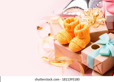Pair of small yellow baby socks and gift box on pink background with gift present boxes and copy space for your warm message, baby shower, first newborn party background, banner