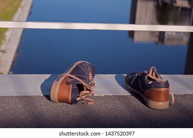 A Pair Of Teenager’s Sneakers On The Edge Of The Bridge Over The River Below. Suicide Concept. 